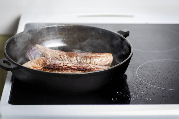 frying beef steaks on a cast iron skillet and an induction cooker - Valokuva, kuva