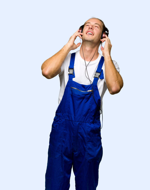 Працівник слухає музику з навушниками на ізольованому фоні
 - Фото, зображення