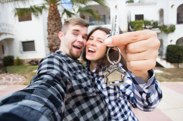 Uusi koti, kiinteistö ja liikkuva konsepti - Hauska nuori pari esittelee avaimet uudesta talosta
. - Valokuva, kuva