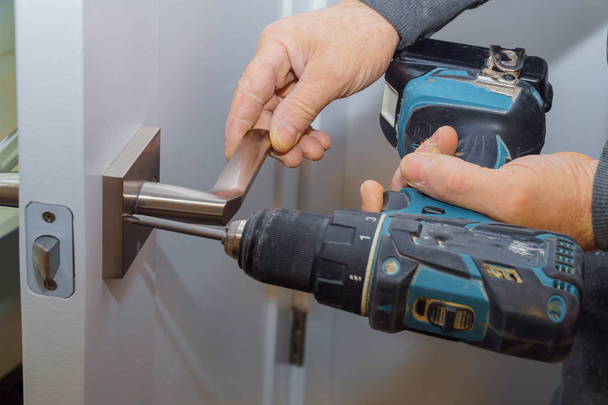 Instalacja zablokowana blokada drzwi wewnętrzne woodworker ręce instalacji instalacji blokady drzwi. - Zdjęcie, obraz