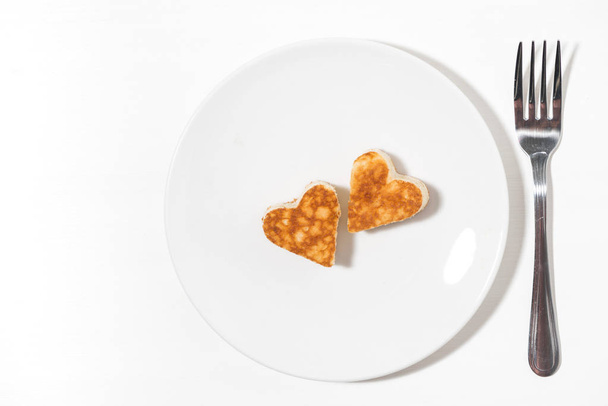 plate of pancakes in the shape of heart and forks on white background, top view - Photo, image