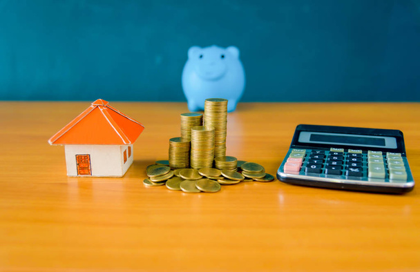 Blauwe varken bank en munten stack en geel papier huis voor geld s - Foto, afbeelding