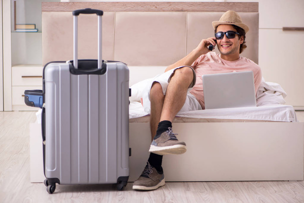 旅行を待っている寝室でスーツケースを持つ男  - 写真・画像