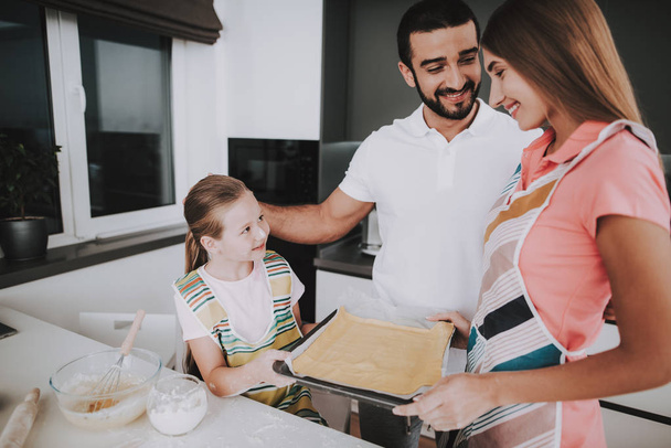 Young Family Is Cooking With Dough At Kitchen. Happy Family Relationship. Making Dish Together. Apron Wear. Active Holiday Leisure. Roll Out Dough. Learn To Baking. Mother And Daughter. - Фото, изображение