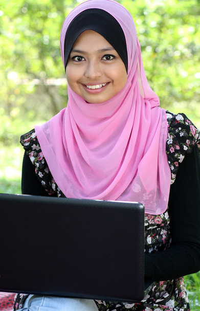 Belle femme musulmane utilisant un ordinateur portable tout en étant assis détendu
 - Photo, image