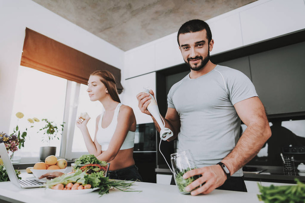 A Couple Is Preparing A Salad For A Breakfast. Cooking Together.. Healthy Lifestyle. Young And Handsome. Sport Body. House Interior. Morning Fresh Nutrition Concept. Mixing With Blender. - Foto, Bild
