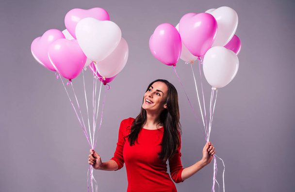 Happy woman posing with balloons on grey background - Fotoğraf, Görsel