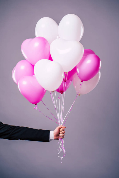 Happy man holding balloons on grey background - Zdjęcie, obraz