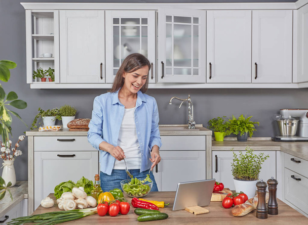 Весела молода жінка готує на кухні з цифровим планшетом
 - Фото, зображення