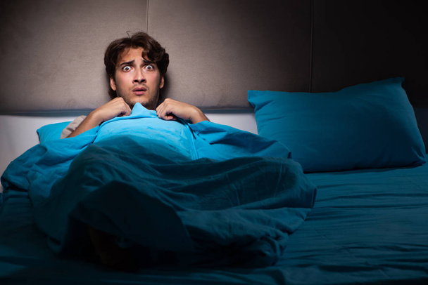 Jeune homme effrayé dans son lit ayant des cauchemars
 - Photo, image
