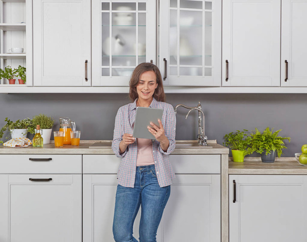 Giovane donna con tablet digitale in cucina
 - Foto, immagini