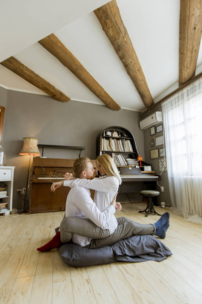 Happy and loving young couple kissing while sitting on the floor in the room - Valokuva, kuva