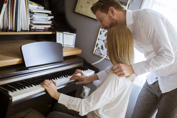 Loving young couple playing piano in the room at home - Zdjęcie, obraz