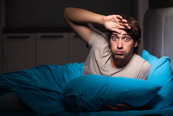junger schöner Mann leidet unter Schlaflosigkeit im Bett - Foto, Bild