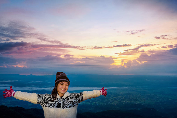 Turista mujer en un vestido de jersey de pie brazos extendidos, feliz mientras observa el hermoso paisaje natural del bosque y la montaña durante el amanecer en Phu Thap Boek Mirador Phetchabun, Tailandia
 - Foto, Imagen