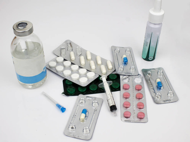 Tabletten, capsules, oplossing fles, neusspray, spuit, naald voor injectie. Geneesmiddelen bevinden zich op een witte achtergrond. - Foto, afbeelding