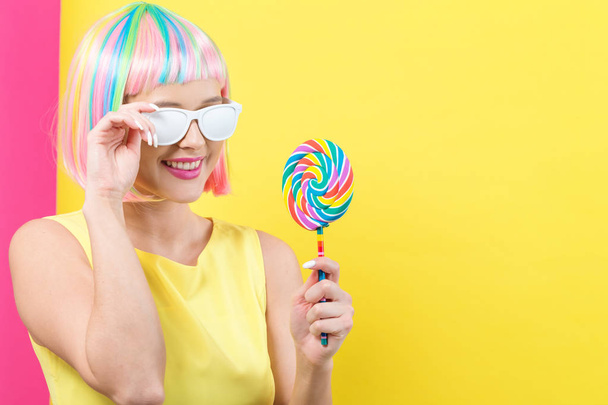 Woman in a colorful wig with a lollipop - 写真・画像