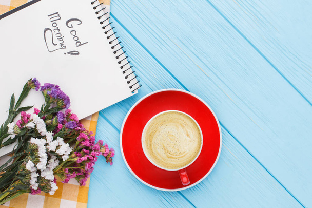 Кофейная кружка с цветами и блокнот с пожеланием доброго утра
. - Фото, изображение