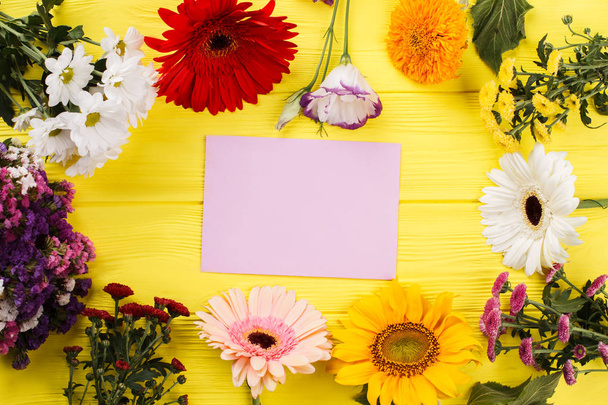 Variety of multicolored blossoming flowers and blank paper. - Foto, afbeelding
