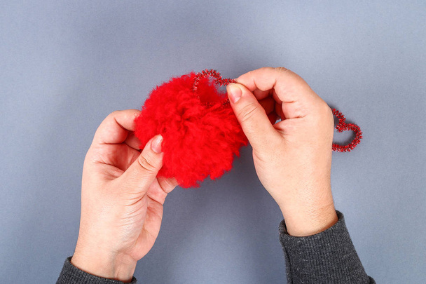 Red handmade diy monster pom pom from yarn, chenille stems in shape heart. Gift ideas for Valentines Day, day of love, the concept of February 14. Step by step. Process of kid crafts. Top view. - Fotó, kép