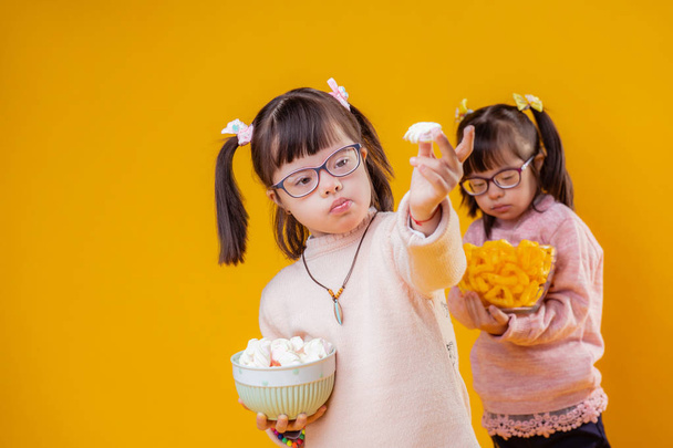 Two adorable children with down syndrome carrying tasty snacks - Foto, afbeelding