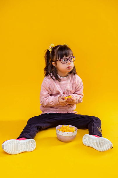 Curious serious little lady sitting on bare floor against bowl - Foto, imagen