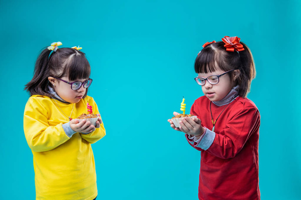niedlichen kleinen Schwestern in bunten Outfits und tragen Cupcakes - Foto, Bild