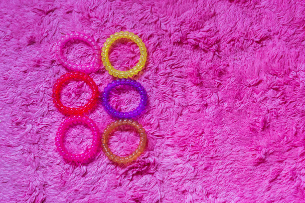 купа еластичності пластикового кабелю в різних кольорах ізольовані на м'якому рожевому фоні, дівчачі аксесуари для волосся
 - Фото, зображення