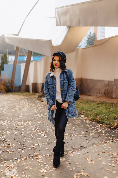 young pretty girl in a denim coat walks in the autumn sunny city - Foto, Imagem