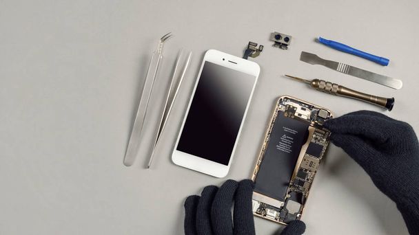 Techniker oder Ingenieur demontieren defekte Komponenten Smartphone und nehmen Logikboard zur Reparatur oder ersetzen neue Smartphone-Logikboard auf dem Schreibtisch mit Kopierplatz - Foto, Bild