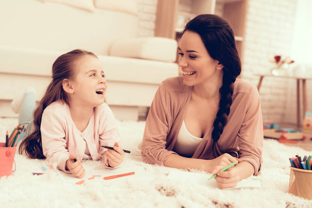Mom Fun with Daughter. Kids Home Games. Rest at Home. Child Development. Mother and Daughter Play. Happy Mom and Child in Pajamas. Girl and Mother Lie on Carpet. Colour Pencils. Mom and Daughter Draw. - Foto, Imagem