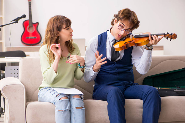 Jonge vrouw tijdens muziekles met mannelijke leraar - Foto, afbeelding