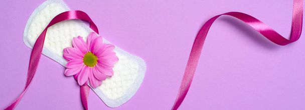 Damenbinden und Gerbera-Gänseblümchen auf rosa Hintergrund, feminines Hygienekonzept, Langformat - Foto, Bild