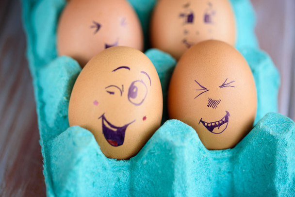 Веселі пончики на великодніх яйцях на синій сковороді. Різні обличчя на яйцях. Емоції
. - Фото, зображення