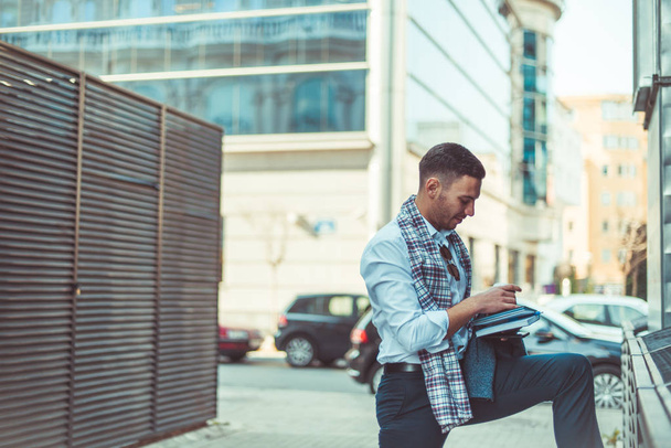 Podnikatel v obleku stojí na jedné noze na ulici a čtení jeho notebook - Fotografie, Obrázek