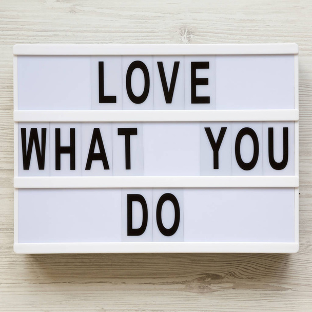 Современная доска с надписью "Любите то, что вы делаете" на белой деревянной поверхности, вид сверху. Бизнес-концепция. Сверху, плоский, над головой
. - Фото, изображение