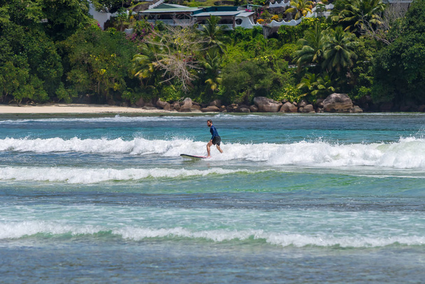 MAHE, SEYCHELLES - SEPTEMBER 25, 2018: Unidentified man surfing on a large wave on island Mahe  on the coast of Indian ocean - is the best surf paradise in Seychelles - 写真・画像