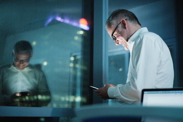 Gelukkig Manager gebruiken Smartphone In donkere Office At Night - Foto, afbeelding