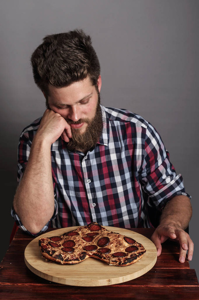 Sad man looking at fail burned heart shaped pizza - Foto, Bild