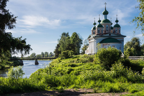 The ancient church rises on an island in the middle of the river. The sun is playing on the domes. The blue sky is reflected in the river. Olonets, Karelia, Russia - 写真・画像