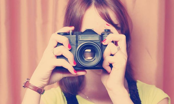 Девушка держит винтажное фото SLR камеры перед лицом
 - Фото, изображение