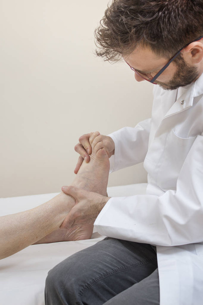 Un medico ortopedico esamina il piede di una donna anziana sdraiata su un letto
. - Foto, immagini