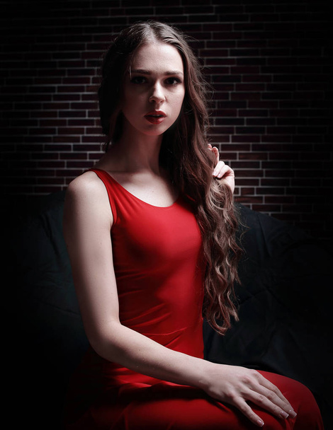 stylish young woman in red dress sitting in big round chair. - Фото, зображення
