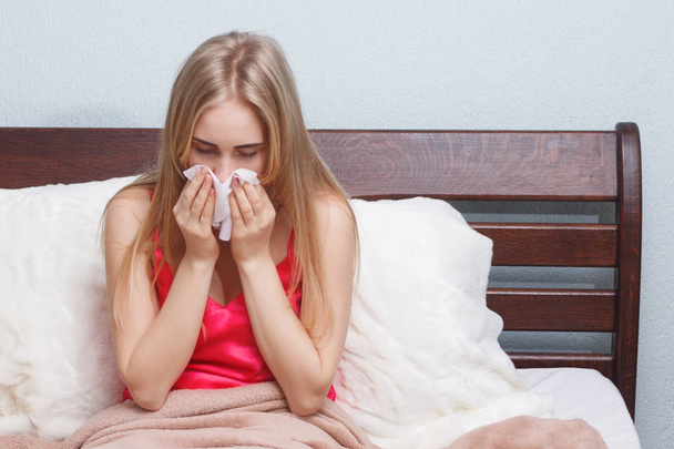 άρρωστη γυναίκα στο κρεβάτι με γρίπη και το κρυολόγημα που είναι φυσάει τη μύτη της  - Φωτογραφία, εικόνα