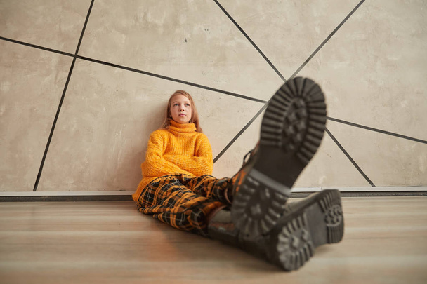 stylized photo of a thoughtful girl sitting near a wall. - Fotó, kép