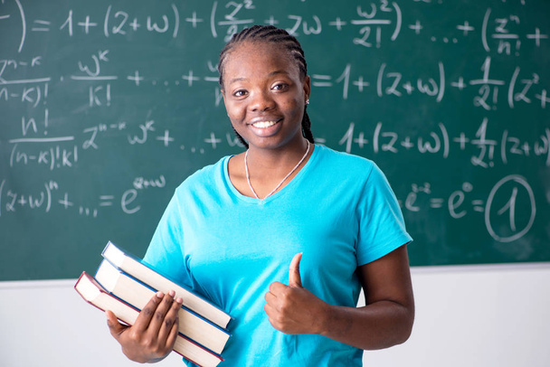 Black female student in front of chalkboard   - 写真・画像