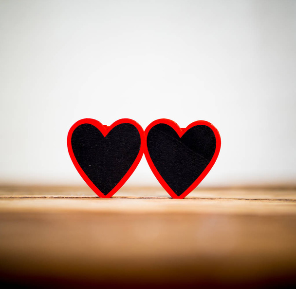 Two red hearts on vintage rustic wooden table and romantic light with background out of focus in Valentines day, love, Mothers Fathers day and Wedding Greeting card concept. Copy space for message. - Photo, image