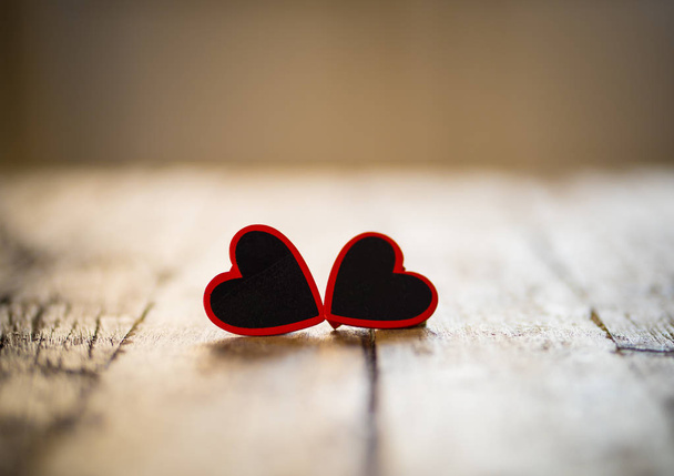Two red hearts on vintage rustic wooden table and romantic light with background out of focus in Valentines day, love, Mothers Fathers day and Wedding Greeting card concept. Copy space for message. - 写真・画像