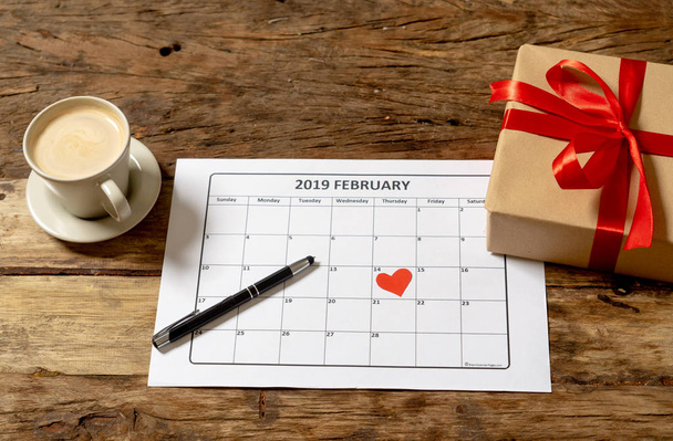 Top view of red heart on the 14 th of february 2019 calendar and present gift wrapped with love you message on vintage table in ready for saint Valentines day date and romantic celebration concept. - Photo, image