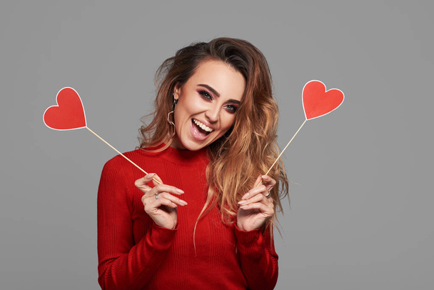 Beauty joyful Young fashion model Girl with Valentine Heart shaped  in her hands. Love Concept. Beautiful smiling young woman. Valentines Day gift. Isolated on grey background, space for text - Photo, image